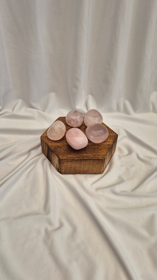 Rose quartz stones in a wooden box on a draped fabric background
