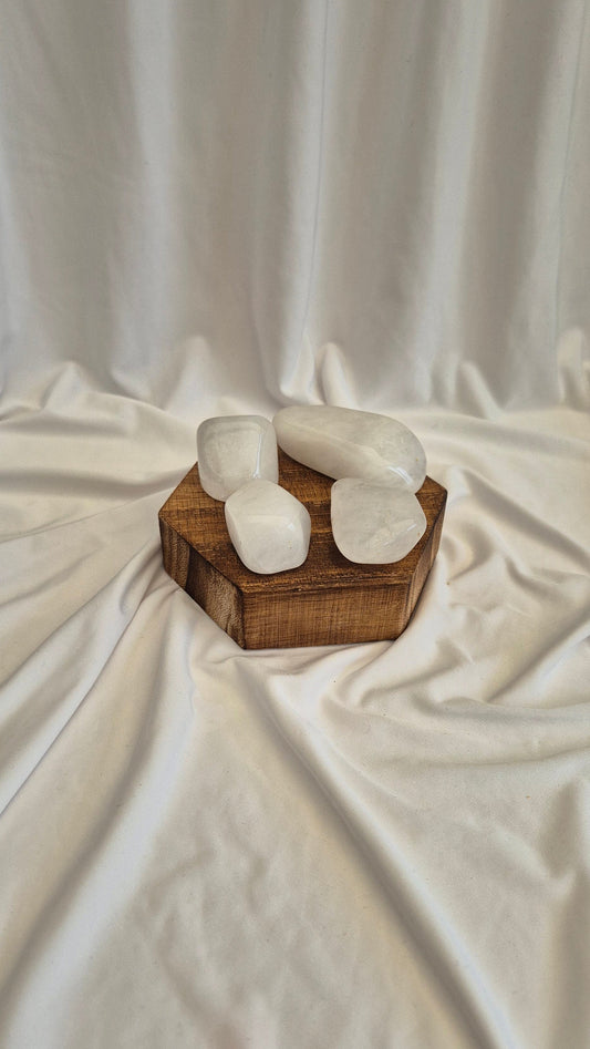 White stone sculpture on a wooden base against a white fabric background