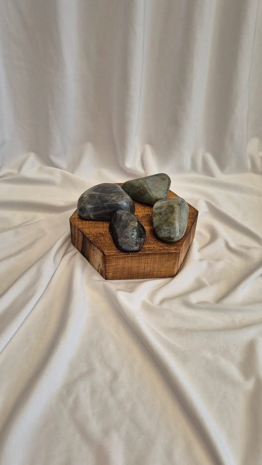 Three stones on a wooden block with a white fabric background
