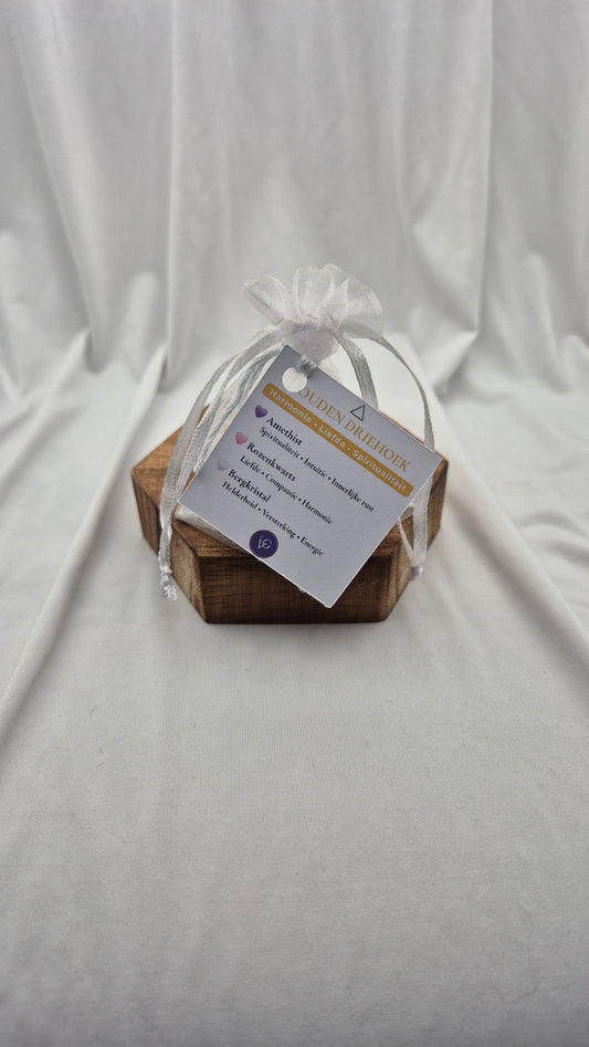 A small wooden keepsake box wrapped in a sheer white ribbon and a paper tag, photographed against draped white fabric.